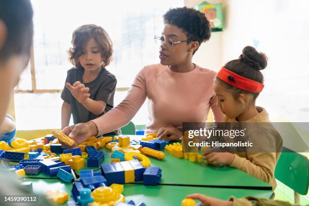 teacher playing with toy blocks in class at the school - child care stock pictures, royalty-free photos & images
