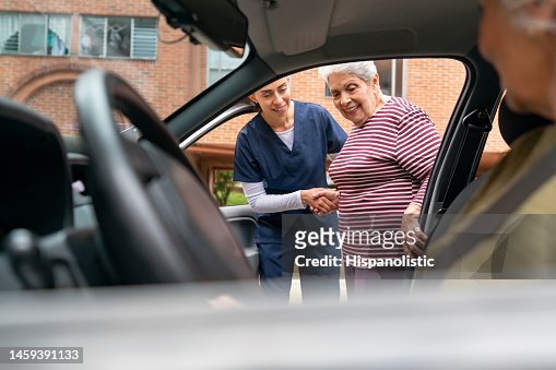 Home caregiver helping a senior woman get in a car