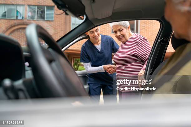 home caregiver helping a senior woman get in a car - riding car stock pictures, royalty-free photos & images
