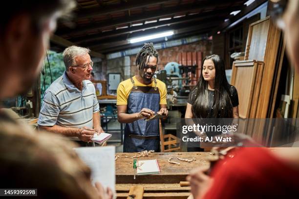 carpenter teaching group of people standing at workbench in woodwork class - carpenter stock pictures, royalty-free photos & images