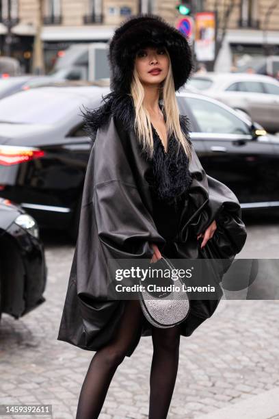 Caroline Hu wears a black leather jacket with fur details, black fur hat and silver strass bag, outside Stephane Rolland, during Paris Fashion Week -...