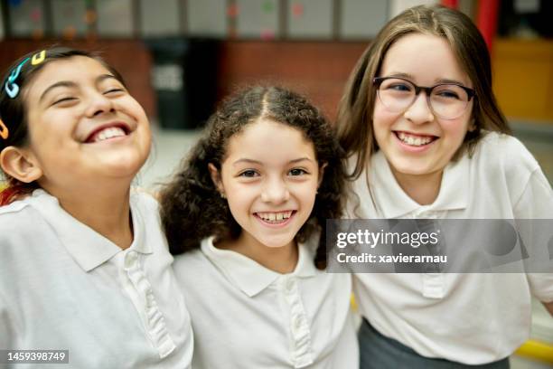 portrait of pre-adolescent schoolgirls - arms around stockfoto's en -beelden