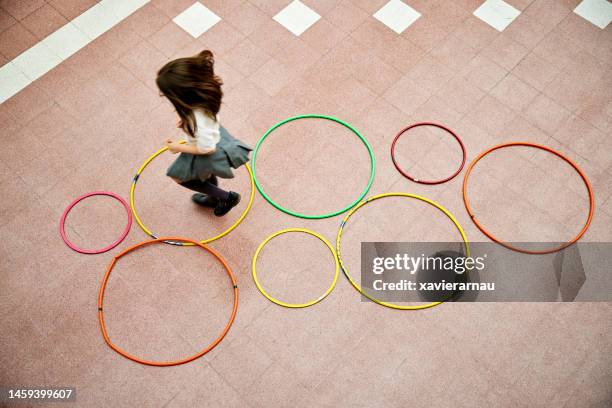 young girl playing hopscotch with plastic hoops - hoelahoep stockfoto's en -beelden