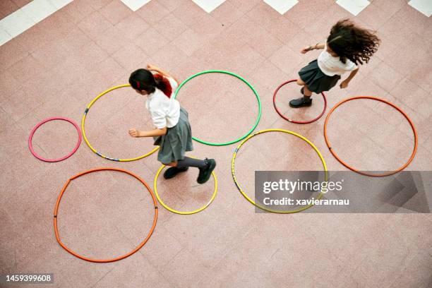two elementary schoolgirls playing hopscotch - speeltuintoestellen stockfoto's en -beelden
