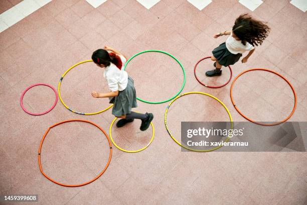 two elementary schoolgirls playing hopscotch - playground equipment stock pictures, royalty-free photos & images