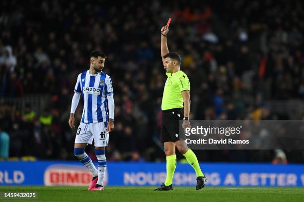 Referee Jesus Gil Manzano shows a red card to Brais Mendez of Real Sociedad, after a Video Assistant Referee review upgraded the foul from a yellow...