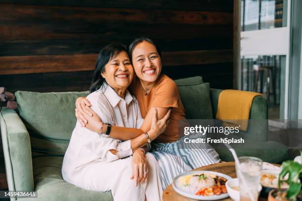 un retrato de una mujer feliz y hermosa abrazando a su madre en el día de la madre mientras están sentados en el café - mother´s day fotografías e imágenes de stock