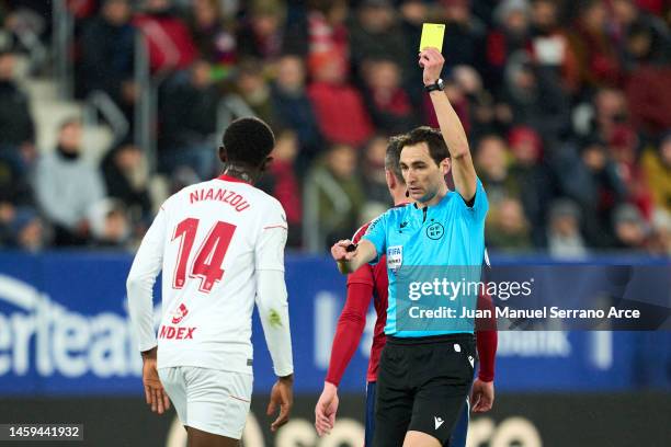 Referee Ricardo De Burgos Bengoetxea shows a yellow card to Tanguy Nianzou of Sevilla FC during the Copa del Rey Quarter Final match between CA...