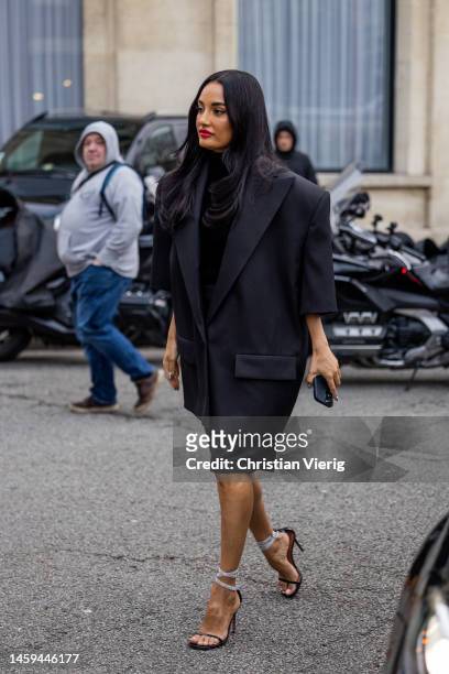Amina Muaddi wears black oversized blazer with short sleeves, heels outside Alexandre Vauthier during Paris Fashion Week - Haute Couture Spring...