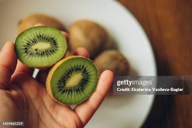 kiwi fruits in female hands on a wooden background, a view of the top. - kiwi fruit stock pictures, royalty-free photos & images