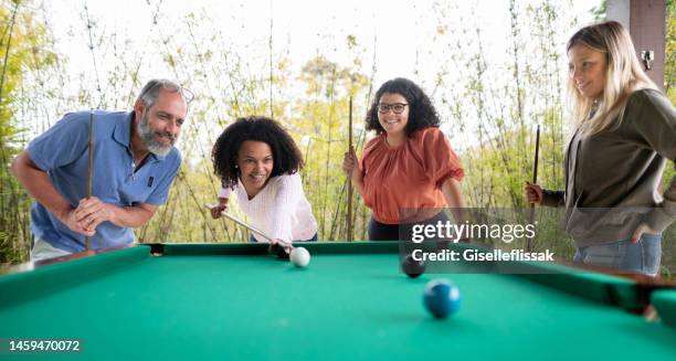 junge frau beim billardspielen mit ihrem vater und freunden draußen auf einer terrasse - billard tisch stock-fotos und bilder