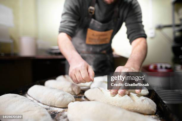 baker scoring loaves of bread before baking them in an oven - bakplåt bildbanksfoton och bilder