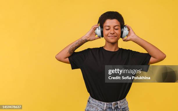 relaxed young black woman in white wireless headphones. - black shirt imagens e fotografias de stock
