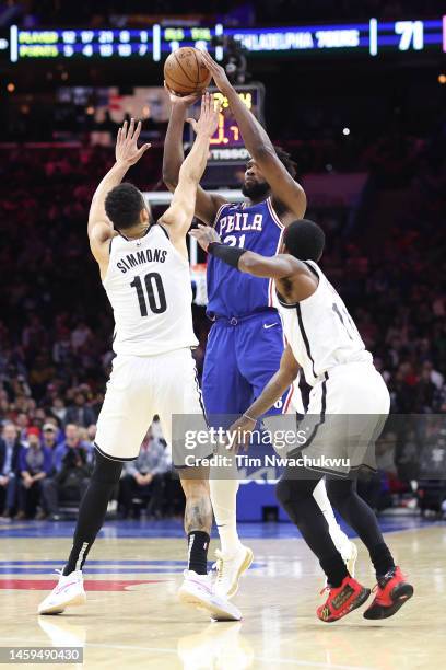 Ben Simmons and Kyrie Irving of the Brooklyn Nets guard Joel Embiid of the Philadelphia 76ers during the second quarter at Wells Fargo Center on...