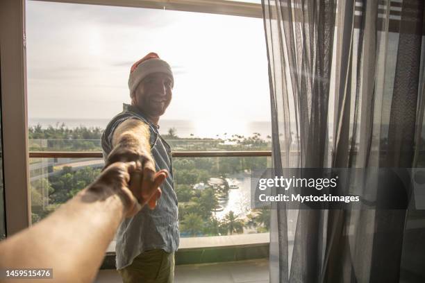 couple wearing santa hats, pov of person following man to hotel room at sunrise, tropical holidays - christmas travel stock pictures, royalty-free photos & images