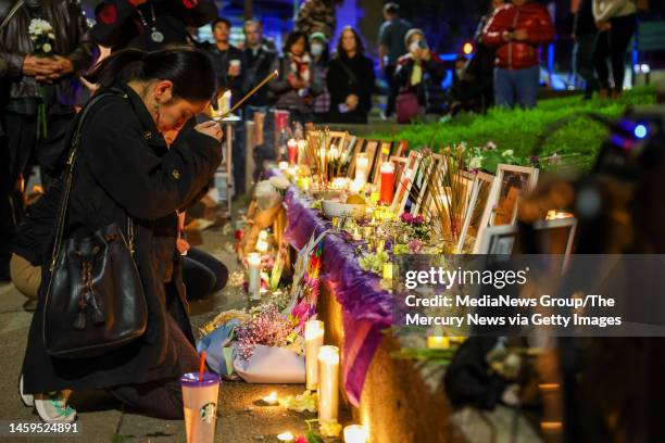 Carina Lieu, of Oakland, pays respects in a makeshift memorial in honor to the mass shooting victims of the Monterey Park, Half Moon Bay and East...