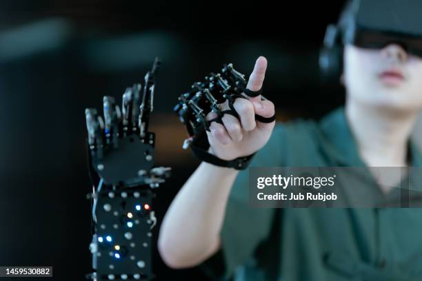 boy pointing hand touching robot hand he wore gloves to control. education learning modern technology. - students plant lab stock pictures, royalty-free photos & images