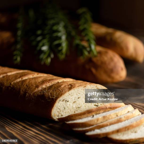 french baguette. loaf is cut into slices. bread made from wheat flour on wooden table. sectional view. dark background. soft focus. copy space - cannes food stock pictures, royalty-free photos & images