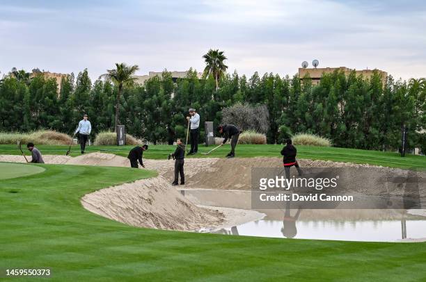 Course workers work on repairing a damaged and flooded green-side bunker on the sixth hole as heavy overnight rain causes a delay in the start of...