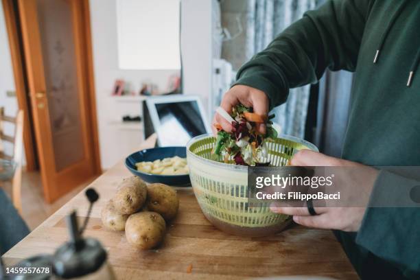 young adult man preparing a fresh salad for lunch - centrifugal force stockfoto's en -beelden
