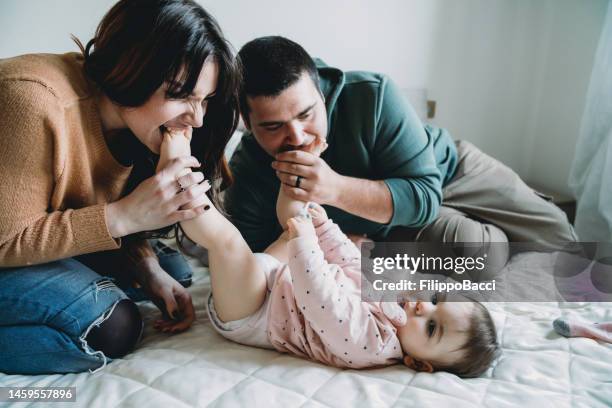 una madre y un padre besando los pies de su pequeña hija - kissing feet fotografías e imágenes de stock