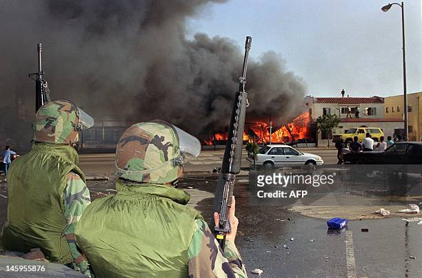 National Guardsmen watch a business go up in flames in South Los Angeles, 30 April 1992. The 1992 Los Angeles riots, with looting and arson events,...