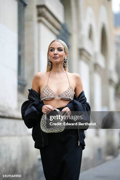 Leonie Hanne wears rhinestones long heart pendant earrings , a rhinestones bra underwear from Elie Saab, a black bomber coat from Elie Saab, a black...