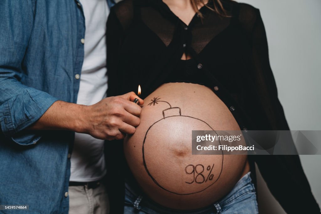 Funny shot of a pregnant couple that are about to detonate the belly
