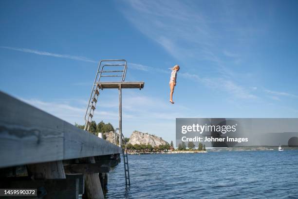 girl jumping from diving tower - sprungturm stock-fotos und bilder