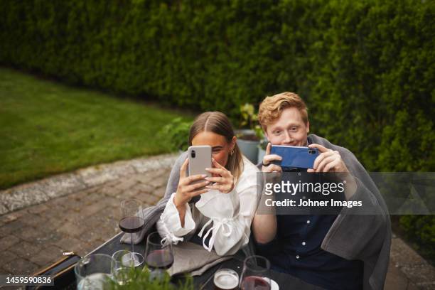 smiling friends taking pictures with cell phones - photographing garden stock pictures, royalty-free photos & images
