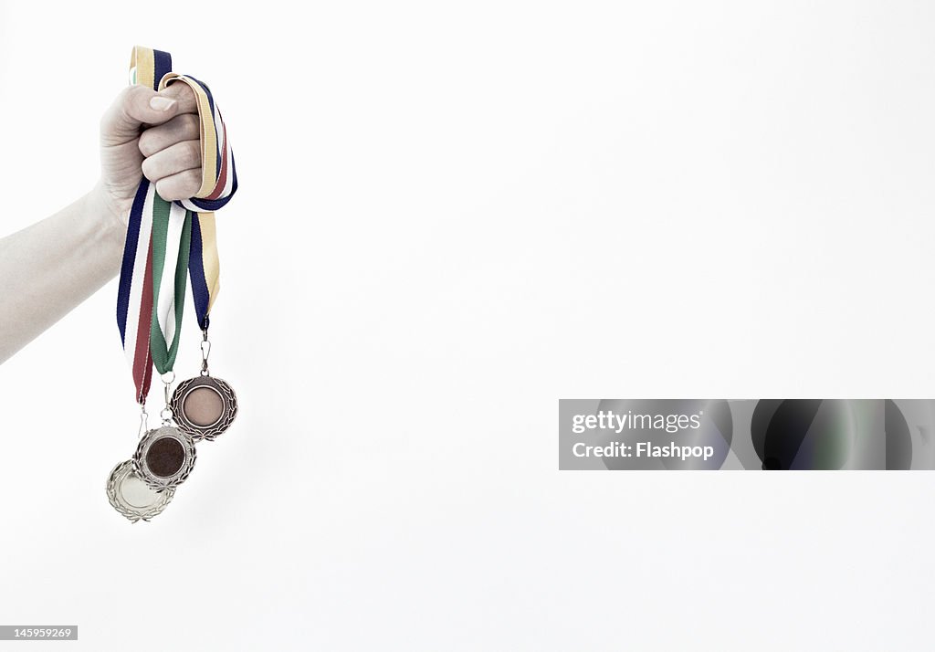 Hand holding gold, silver and bronze medals
