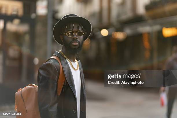 portrait of black man looking at the camera on a city street - vestimenta stockfoto's en -beelden