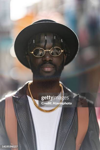 portrait of black man looking at the camera on a city street - vestimenta foto e immagini stock