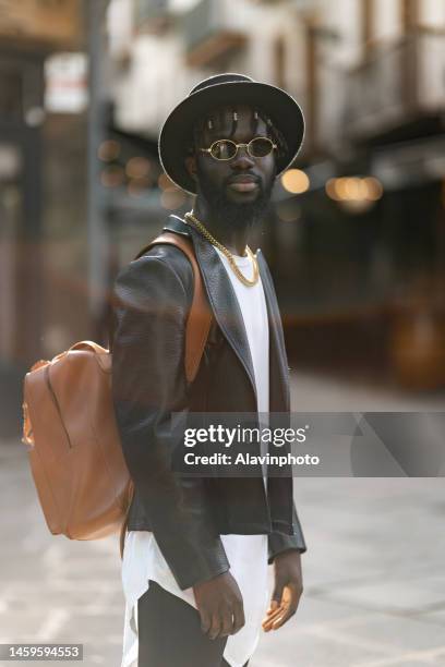 portrait of black man looking at the camera on a city street - vestimenta stockfoto's en -beelden