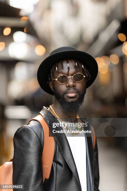 portrait of black man looking at the camera on a city street - vestimenta stock-fotos und bilder