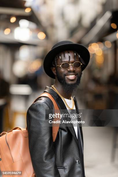 portrait of black man looking at the camera smiling  on a city street - vestimenta stockfoto's en -beelden