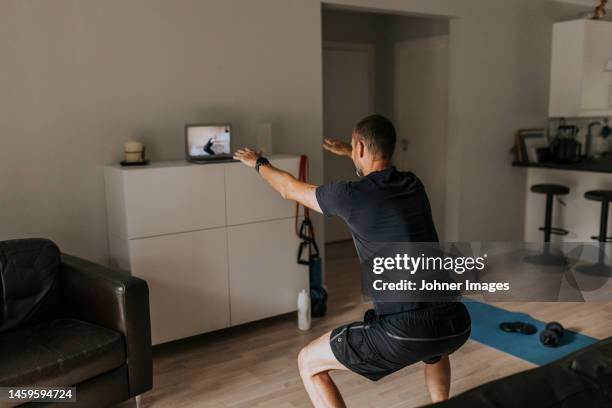 man doing squats at home - home workout foto e immagini stock