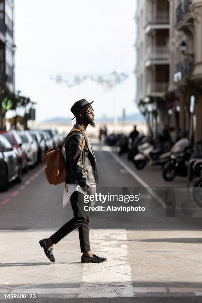 black man crossing a crosswalk in a city - vestimenta stock pictures, royalty-free photos & images