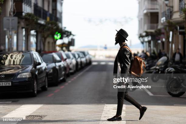 black man crossing a crosswalk in a city - vestimenta stock pictures, royalty-free photos & images