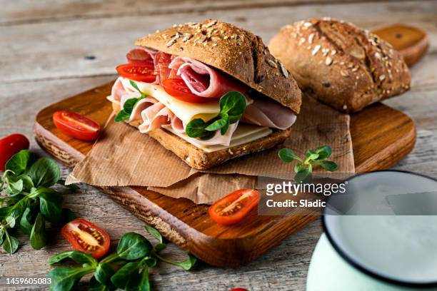 a delicious sandwich with ham, prosciutto, cheese and vegetables - fatia imagens e fotografias de stock