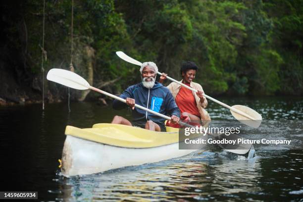 laughing couple paddling a double canoe together down a river - canoeing stock pictures, royalty-free photos & images
