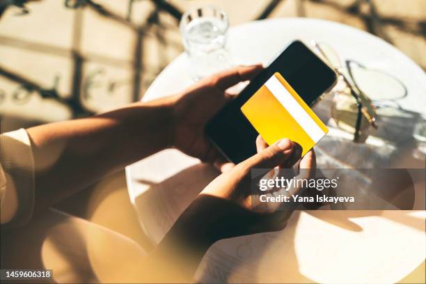 woman using a credit card to pay online bills using mobile application - ポイントカード ストックフォトと画像