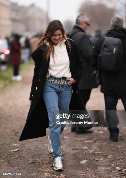 Eugénie Trochu seen wearing a Chanel Look , black long coat, blue denim jeans, beige sweater, a Chanel belt and sneaker and a white chanel bag,...