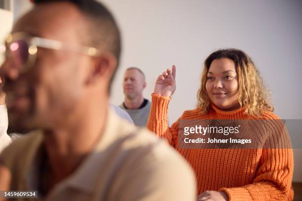 woman raising hand during workshop - 20 to 35 year old in class stock pictures, royalty-free photos & images