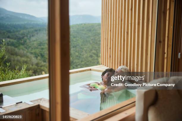 loving couple lying together in a hot tub with a scenic view - hot wife stockfoto's en -beelden