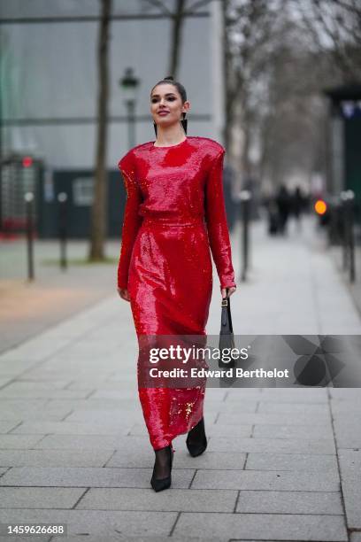 Guest wears black large triangular pattern pendant earrings, a red shiny sequined shoulder-pads / belted / long dress, a black shiny leather handbag,...