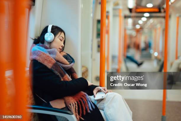 young asian woman with headphones taking a nap on the train - metro de londres imagens e fotografias de stock