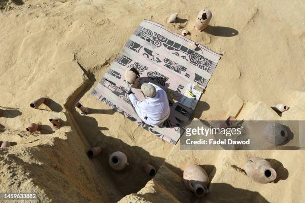 An Egyptian archaeologist restores antiquities after the announcement of new discoveries in Gisr el-Mudir in Saqqara, on January 26, 2023 in Giza,...