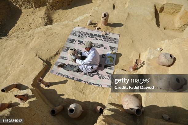 An Egyptian archaeologist restores antiquities after the announcement of new discoveries in Gisr el-Mudir in Saqqara, on January 26, 2023 in Giza,...