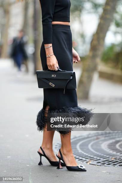 Guest wears a black long sleeves / cropped top, a black high waist with embroidered borders feathers midi tube skirt, diamonds rings, a white gold...